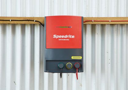 Speedrite 46000W AC powered electric fence Energizer connected to fence and mounted on a barn wall with power light bar flashing