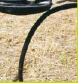 Close-up of a black electric fence insulator tube on a textured surface